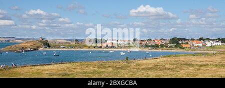 View across the harbour and bay towards the priory ruins and village on Lindisfarne, Northumberland Stock Photo