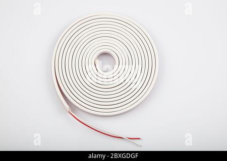 White flexible led tape neon flex. White Neon Flexible strip light 5 meters Watch on white background. Stock Photo