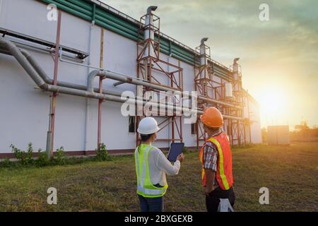 Two engineers standing outside a power plant, Thailand Stock Photo