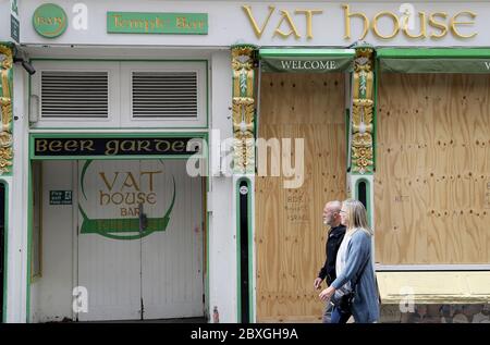 People walk by a boarded up pub in the Temple Bar area of Dublin. Bars will be able to reopen on June 29th if they serve food and have table service only, as phase two of Ireland's coronavirus recovery road map comes into effect on Monday 8th June along with other measures originally envisaged for later phases. Stock Photo