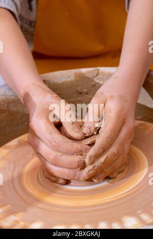 The hands of a teenager potter, making an earthen jar. Vertical Stock Photo