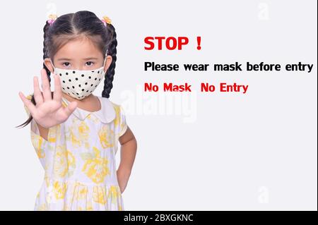 Asian little girl wearing protective face mask, making stop hand sign on white background for preventing the spread of Covid-19 the pandemic concept Stock Photo