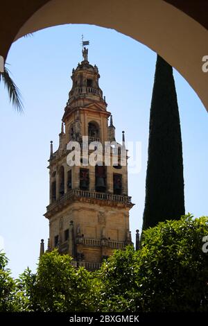 Bell tower of the Great Mosque Cathedral of Cordoba seen through an arch in strong afternoon sunlight on a hot day in May Andalusia Spain Stock Photo