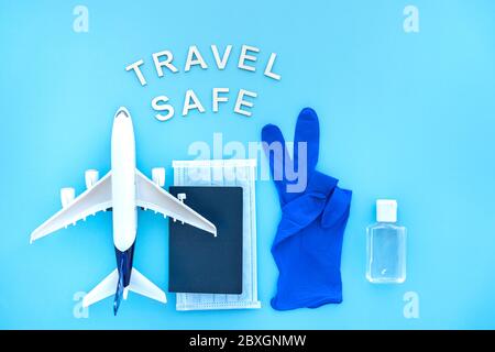 Travel after pandemic. Travel safe after coronavirus. Plane, Blue passport with medical mask, Protective gloves, Bottle of Hand Sanitizer. Stock Photo