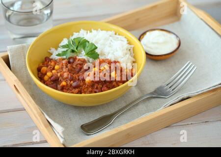 Chili con carne with long-grained rice decorated with a leaf of parsley and served with sour cream Stock Photo