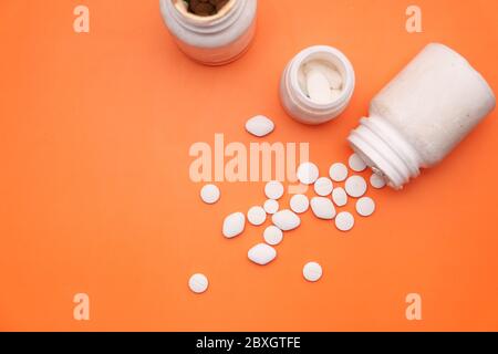 Top view of white pills spilling from container  Stock Photo