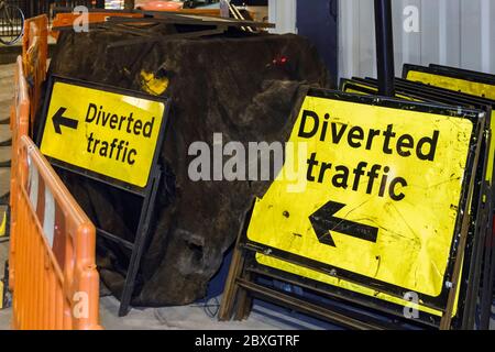 A stack of 'Diverted Traffic' signs by the side of the road at night, London, UK Stock Photo