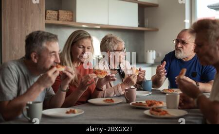 Mature friends sitting at the table in the home kitchen. Stock Photo