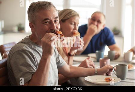 Mature friends sitting at the table in the home kitchen. Stock Photo