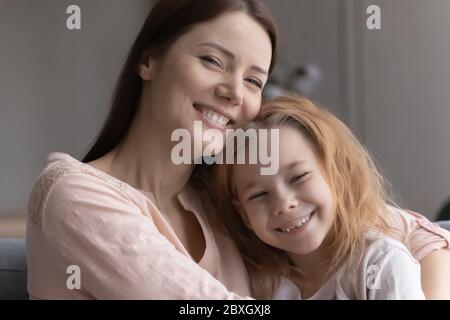 Portrait of smiling young mom and little daughter hugging Stock Photo