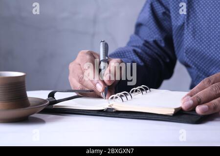 young man writing on notepad at office desk  Stock Photo