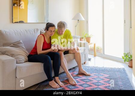 Middle-aged couple sitting on the sofa and communicating with cell phone Stock Photo