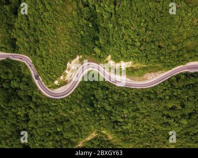 Aerial top down view: of cars driving on zig zag winding mountain road Stock Photo