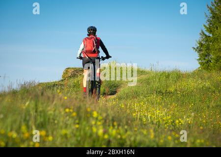 pretty senior woman riding her electric mountain bike on the mountains above Oberstaufen, Allgau Alps, Bavaria Germany Stock Photo