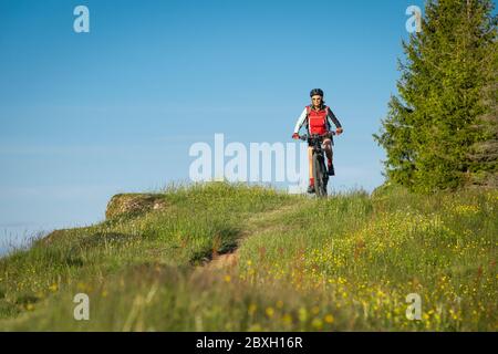 pretty senior woman riding her electric mountain bike on the mountains above Oberstaufen, Allgau Alps, Bavaria Germany Stock Photo