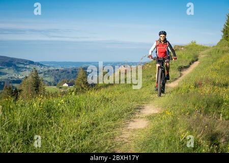 pretty senior woman riding her electric mountain bike on the mountains above Oberstaufen, Allgau Alps, Bavaria Germany Stock Photo