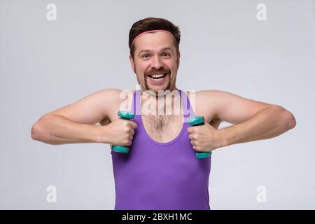 Athletic funny young man doing exercise dumbbell. Studio shot Stock Photo