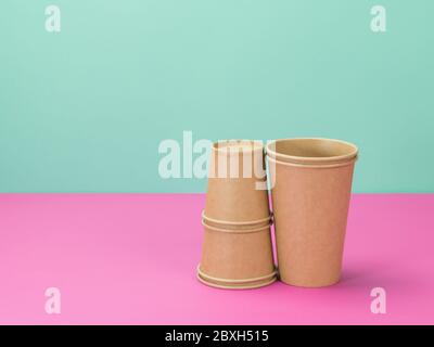 Paper cups disposable on pink and turquoise background. Eco cups. Stock Photo