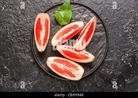 Plate with fresh sliced grapefruit on dark background Stock Photo