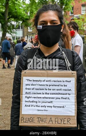 A young woman in a mask with a placard about anti racism at a demonstration in support of 'Black Lives Matter'. London UK. Stock Photo