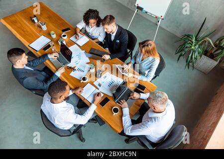 Coworkers Working Sitting At One Desk Using Gadgets In Office Stock Photo