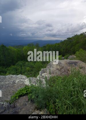 The storm clouds are parting and the sun shines through onto the land below. Stock Photo