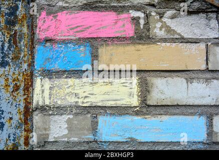 Close up of part of a gray brick wall with with colour chalk on it. Bricks shaded by children colorful crayons Stock Photo