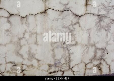 Damaged distressed concrete wall with large cracks. Texture of old white cement wall with cracks Stock Photo
