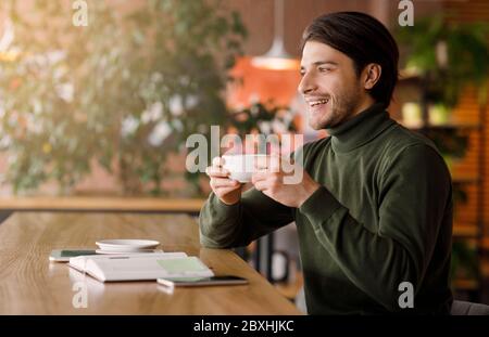 Dreamy freelancer looking for new opportunities, drinking coffee Stock Photo