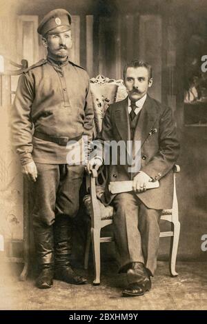 RUSSIA / Latvia - CIRCA 1916-1917: An antique photo shows Russian soldier and civilian person during World War One posing in front of a camera in stud Stock Photo