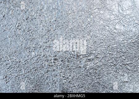 Crumpled tin foil surface, top view. Abstract full frame textured silvery background. Stock Photo