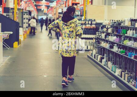 Woman in protective mask at the mall. Alarmed female wears medical mask against coronavirus while grocery shopping in supermarket, safety and pandemic Stock Photo
