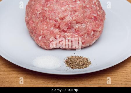 Minced pork on a plate with spec. Homemade meat semi-finished products. Minced pork. Semi-finished products for storage in the refrigerator Stock Photo