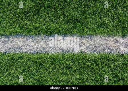 Green grass and white border lines on football ground. Soccer field on artificial turf. Artificial green grass texture. Artificial football field in a Stock Photo