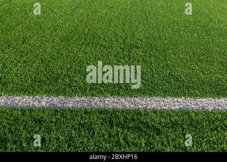 Green grass and white border lines on football ground. Soccer field on artificial turf. Artificial green grass texture. Artificial football field in a Stock Photo