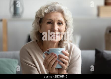 Portrait of smiling mature woman enjoying hot tea Stock Photo