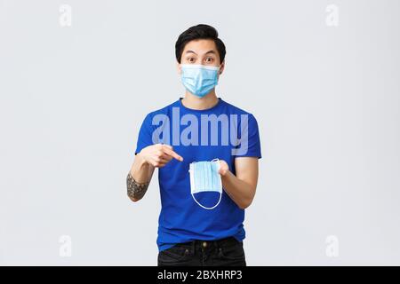 Different emotions, social distancing, quarantine on coronavirus and lifestyle concept. Excited asian man in protective equipment, pointing finger at Stock Photo