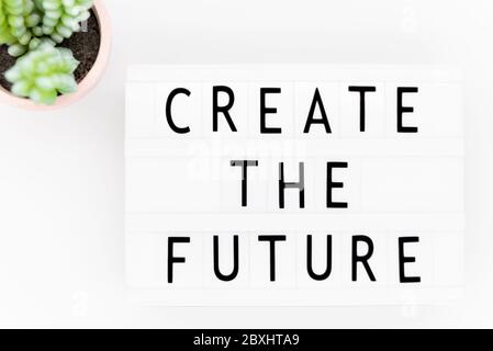 Create the future: words on lightbox on a white wooden surface, top view. Stock Photo