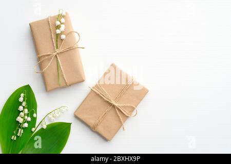 Two gift boxes with minimalist style wrapping design and lily of the valley flowers on white background, top view. Flat lay composition for Wedding, M Stock Photo