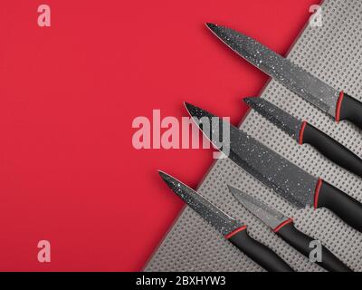Kitchen knife set in a silver base on a red background. Stock Photo