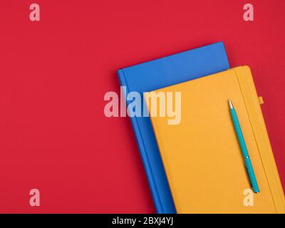 Bright business notebooks and pen on red background. Stock Photo