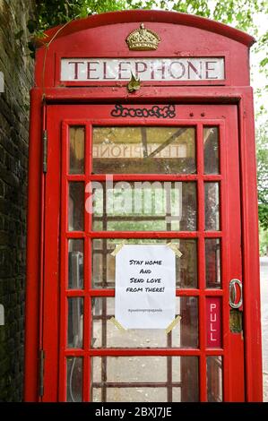 A notice placed on a UK red telephone box 'Stay home and send love from there'. Stock Photo
