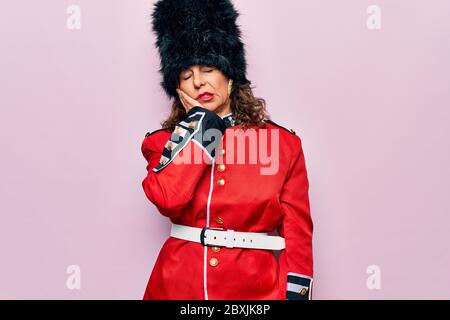 Middle age beautiful wales guard woman wearing traditional uniform over pink background thinking looking tired and bored with depression problems with Stock Photo