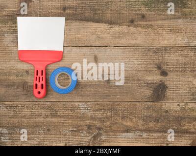 Painting putty knife and duct tape on wooden background. The view from the top. Stock Photo