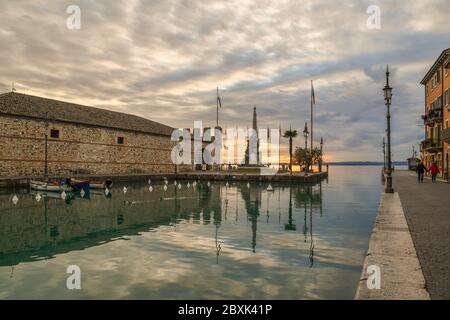 View of the harbor of the old town on the shore of Lake Garda with the Venetian Customhouse (Dogana Veneta) at sunset, Lazise, Verona, Veneto, Italy Stock Photo