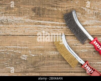Brass and steel brush for metal on wooden background. Stock Photo