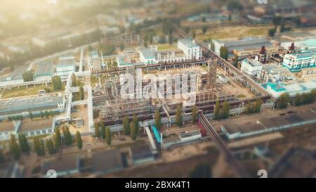 Aerial view of Chemical factory with tanks storages steel pipelines, industrial zone area, tilt-shift view like little toy buildings with blurred background. Stock Photo