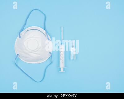 Respirator, syringe and ampoule on blue background. Stock Photo