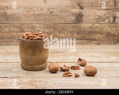 Walnuts in a wooden mortar on wooden background. Stock Photo