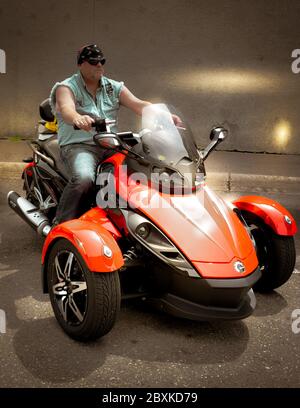 A white biker on three wheels, wearing a bandana riding a BRP Can-Am Spyder Trike, in St. Cloud, MN, USA Stock Photo